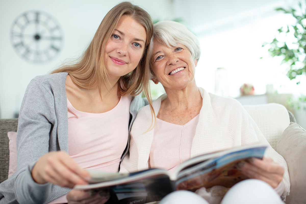 Avail | Senior woman looking through photo book with younger woman